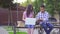 Young asian students man with a book and a woman with a laptop sitting on a bench slow mo