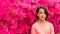 Young Asian teen standing in front of pink azalea flowers in tshirt on hot spring day