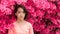 Young Asian teen standing in front of pink azalea flowers in tshirt on hot spring day