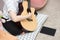 Young asian teenager brunette girl with long hair sitting on the floor and playing an black acoustic guitar on gray wall