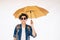 Young Asian tourist smiling and holding umbrella over white background. Alone and Looking for partner to travel.