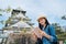 Young asian traveler holding guidebook visiting historical osaka castle with clear blue sky in the background. female tourist