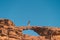 Young Asian traveller walking on natural rock bridge in Wadi Rum desert in Jordan, Arab, Asia