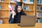 A young Asian university graduate woman in graduation gown expressing joy and excitement to celebrate her education achievement in