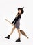 Young asian witch girl in black halloween costume wearing witch hat and holding witch broom posing on white background