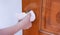 Young Asian woman adult opening door with clean tissue on the knob handle instead of hand, concept of antibacterial, virus