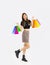 Young asian woman in black crop top t-shirt striped skirt and ankle boots carrying colorful paper shopping bags posing on white