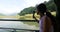 A young Asian woman on the boat in the lake with action camera filming video.