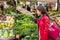 Young Asian woman buying fresh vegetables at farmers food market with shopping bag. Chinese Caucasian girl walking at outdoor