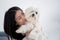 Young asian woman carrying and kiss with fluffy dog shih tzu with love in living room at home, friends pet.