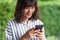 Young Asian woman chatting and searching with smartphone. A happy girl enjoying outdoor lifestyle surrounded by greeny plant.