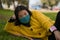 Young Asian woman in city park during covid19 - outdoors lifestyle portrait of happy and pretty Japanese girl in face mask lying