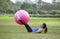 young asian woman doing exercise legs with gym ball in the green nature
