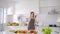 Young asian woman drinking juice near salad table while Young woman watching cellphone in kitchen