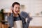 Young asian woman dusting while listening to music with headphones in a bright, organized living room.