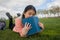 Young Asian woman enjoying novel on grass - lifestyle portrait of young happy and pretty Japanese girl reading a book at beautiful