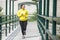 Young asian woman exercising outdoor in yellow neon jacket, jogging