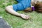 Young Asian woman fainting on grass in park in summer because outdoors of hot weather