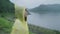 Young Asian woman feeling happy playing rain while wearing raincoat standing near lake.