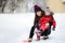 Young asian woman helping caucasian toddler boy with his winter clothing