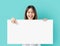 Young Asian woman holding blank paper with smiling face and looking on the blue background. for advertising signs.