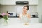 Young asian woman holding milk glass bite cookie in her kitchen