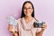 Young asian woman holding vintage camera and swedish krona smiling with a happy and cool smile on face