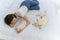 Young asian woman lying and sleeping on white bed with maltese and white Shiba Inu puppy