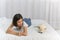 Young asian woman lying with white Shiba Inu puppy sleeping on white bed, Cheerful and nice couple with people and pet. Pet Lover