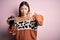 Young asian woman making a glass of coffe using french press coffee maker over pink background with angry face, negative sign