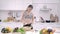 Young Asian woman making salad healthy food while using mobile phone for looking recipe in the kitchen.