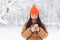 Young Asian woman, in the park on a date, waiting, on a winter snowy day, online uses the phone