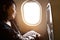 Young asian woman on passenger seat near window in airplane..Traveller sitting inside plane at the airport with sky and sun light