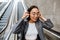 Young asian woman putting on headphones while standing outdoors