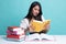 Young Asian woman read a book with books on table