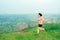 Young Asian woman runner, wearing black sportswear, running on a big mountain trail, cool morning, windmills, and sky in the