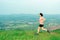 Young Asian woman runner, wearing black sportswear, running on a big mountain trail, cool morning, windmills, and sky in the