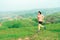 Young Asian woman runner, wearing black sportswear, running on a big mountain trail, cool morning, windmills, and sky in the