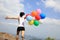 Young asian woman running with colored balloons