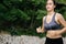 Young Asian woman running on the green countryside. Girl jogging workout at nature forest park.