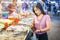 Young asian woman shopping for squid on ice in local market stall with fresh seafood