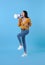 Young Asian woman shouting into megaphone making announcement in isolated on blue background