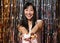 Young asian woman show cupcakes to the camera over a party background.