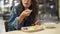 Young Asian woman sitting in cafeteria eating meal. Beautiful Asia girl having dinner alone