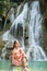 Young Asian woman sitting on a chair In front of the Khoun Moung Keo Waterfall