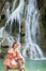 Young Asian woman sitting on a chair In front of the Khoun Moung Keo Waterfall