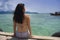 Young Asian woman sitting happy on sea dock at Thailand beach looking at the horizon beautiful marine landscape with mountains enj