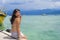 Young Asian woman sitting happy on sea dock at Thailand beach looking at the horizon beautiful marine landscape with mountains enj