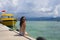 Young Asian woman sitting happy on sea dock at Thailand beach looking at the horizon beautiful marine landscape with mountains enj