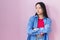 Young asian woman standing over pink background looking to the side with arms crossed convinced and confident